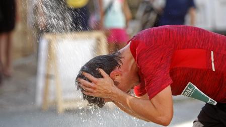 Un corredor, refrescándose durante una carrera popular en verano