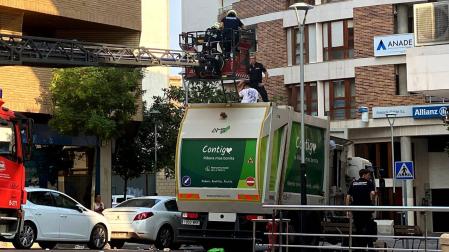 Instante de la actuación de los bomberos y de la Policía Nacional para bajar al mozo que se había subido a lo alto del camión de recogida de basura