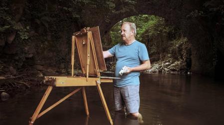 Tomás Sobrino manos a la obra pinta metido en el agua, bajo el puente del molino de Elbete