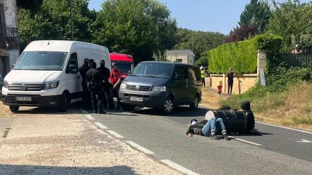 Los dos manifestantes en medio de la calzada atados al barril y agentes de la Policía Foral al fondo de la imagen