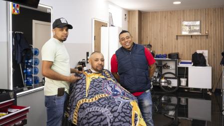Eric Soto y Joel Alexander de la Cruz, barberos de MLB Barbershop (Sarriguren), atendiendo a su cliente Ricardo Herrera