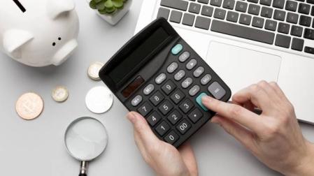 Imagen de una calculadora junto a una hucha