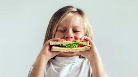 Una niña, comiendo un bocadillo