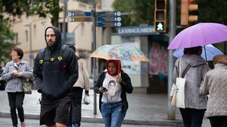 Varias personas con paraguas pasean por una de las calles de Barcelona bajo la lluvia