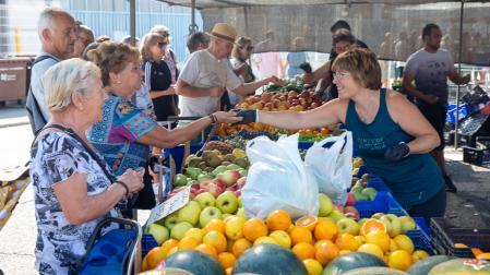 Varias personas compran en uno de los puestos de fruta y verdura del mercadillo de Landaben