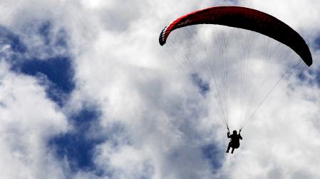 Un practicante de parapente se abalanza sobre un mar de nubes bajas