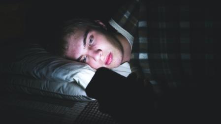 Un adolescente, con un dispositivo móvil en la cama