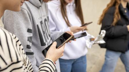 Un grupo de jóvenes observa sus teléfonos móviles en un centro escolar