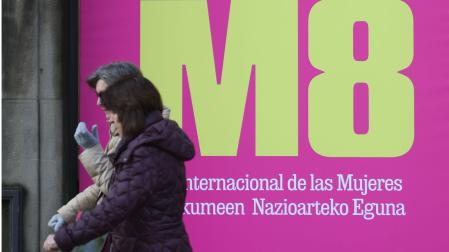Dos personas pasan por delante de un cartel de la campaña lanzada con motivo del Día Internacional de la Mujer, habitual entre las acciones de sensibilización del Gobierno de Navarra