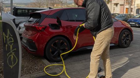 Un automovilista prepara el cable de recarga para enchufar un Cupra Born en una calle de Viana