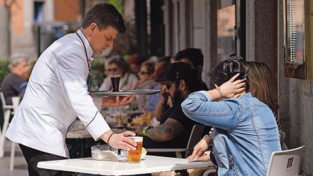 Un camarero sirve su consumición a unas clientes en una terraza madrileña
