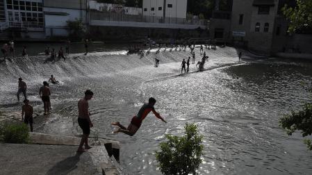 Fotos de los bañistas en el río Arga, junto al Molino de Caparroso, en Pamplona, en una jornada de intenso calor.