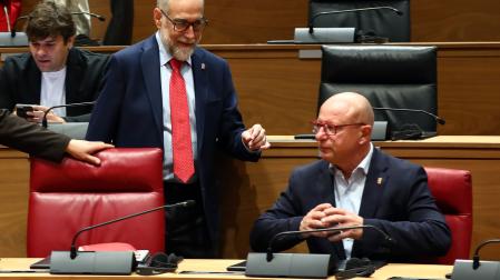 El consejero de Salud, Fernando Domínguez, conversa con el de Educación, Carlos Gimeno, en el pleno de este jueves