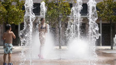 Una niña pasa entre los chorros de agua de la fuente de Yamaguchi, en Pamplona