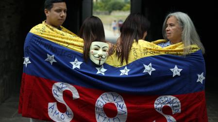 Ali Gómez, Eglee Torres y otras dos compatriotas, que prefieren no identificarse por temor a posibles represalias en su país, se envuelven en una bandera de hilo tejida en 2014 para manifestarse contra el régimen de Nicolás Maduro