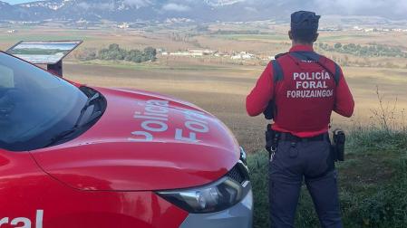 Un agente de la Policía Foral junto a una patrulla /