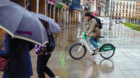 Un usuario del sistema de alquiler de bici eléctrica, ayer bajo la lluvia.