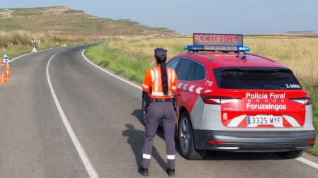 Una policía foral señaliza con su vehículo el lugar de un accidente anterior