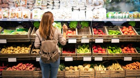 Una mujer, en la sección de verduras de un supermercado