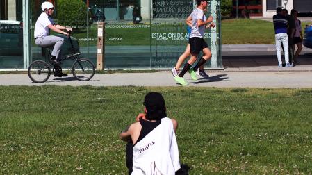 Una persona se sienta y observa pasar a otras en una tarde solada la Vuelta del castillo de Pamplona /