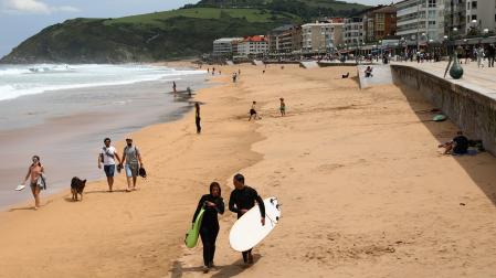 En una imagen de archivo, dos surfistas caminan con sus tablas en la playa de Zarautz.