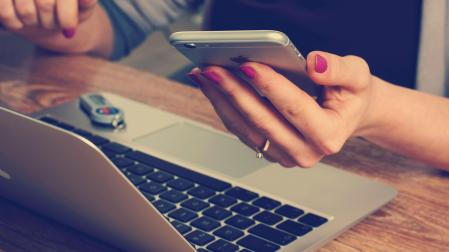 Una mujer consulta el móvil al mismo tiempo que utiliza el ordenador
