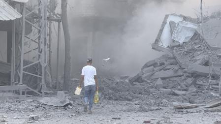 n hombre camina por los escombros tras uno de los ataques lanzados este domingo por Israel en Gaza