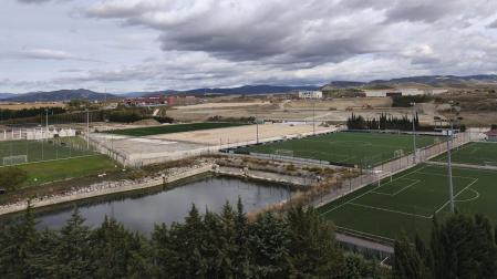Una vista general de ayer de Tajonar con los terrenos actuales y las obras de la zona nueva al fondo, con los dos primeros campos de hierba artificial (uno se ve casi acabado) y el movimiento de tierras que ha habido para asentar el próximo edificio, los dos campos donde entrenará el primer equipo y el estadio para el Promesas y el Femenino.