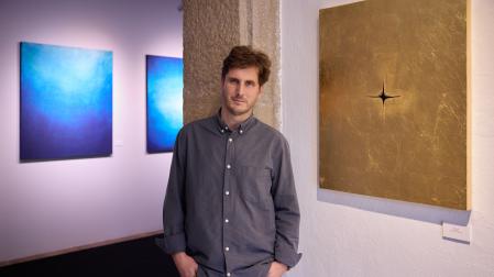 El artista Alberto Guerrero posa en La Puerta Gótica, entre las obras que componen la serie 'Vacío' (doradas) y las que componen la serie 'Misterio' (azules)