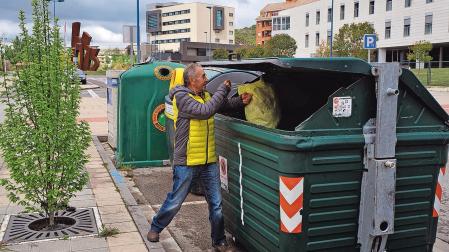 Un hombre deposita basura en un contenedor de Tafalla