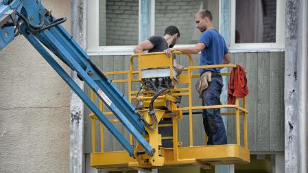 Dos operarios, realizando obras en una fachada