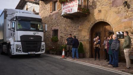 Un camión circula por delante de la casa Sansiñenea, en presencia de varios vecinos de Arraitz.