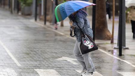 Una mujer se protege del viento con su paraguas con la llegada de la borrasca Claudia