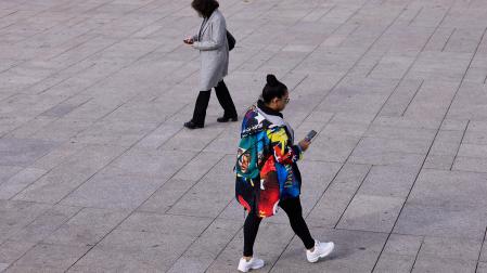 Dos mujeres observan su móvil mientras caminan por la Plaza del Castillo /
