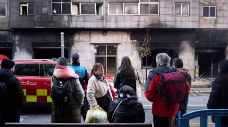 Vecinos y curiosos observan los efectos del fuego en el edificio tras el incendio de un bazar en la Rochapea