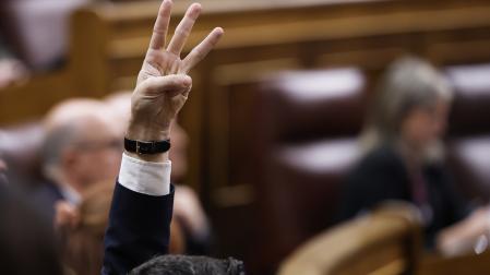 Un diputado del PSOE señala el sentido del voto de la formación durante un pleno que el Congreso celebró este jueves