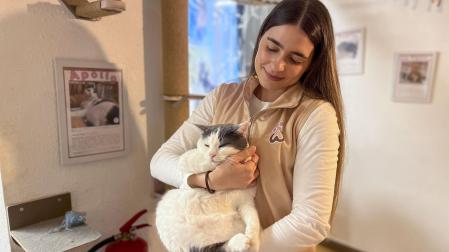 La recepcionista y social media manager de Paws for a moment posa con un gato gris y blanco en la cafetería ubicada en el centro de Málaga