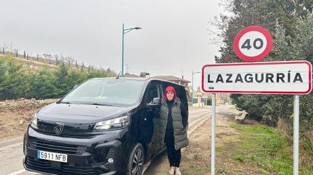 Blanca Baquedano Díaz, con su taxi y un cartel de su pueblo, Lazagurría.