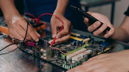 Dos personas trabajando en una placa electrónica