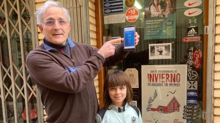 El dueño delante de la tienda deportes donde expendio de máquina el décimo premiado con el gordondel Niño , Serafín García Segura y su sobrina Vega García Sainz