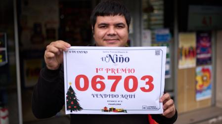 Andrey Mendes muestra con orgullo el cartel con el número agraciado delante de la administración de loterías en el número 52 de la avenida de Barañáin