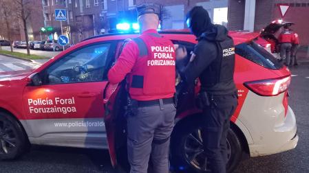 Un agente de la Policçia Foral y otro de la Policía Nacional introducen al agresor en un coche patrulla