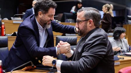 Ramón Alzórriz saluda efusivamente entre risas al nuevo consejero, Javier Remírez, durante el último pleno