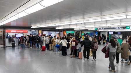 Decenas de personas haciendo cola en oficinas de alquiler de coches, en la estación Madrid-Puerta de Atocha-Almudena Grandes