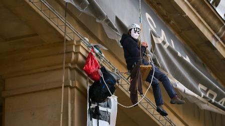 Dos personas con casco y mascarilla han desplegado este viernes por la mañana tres pancartas en la fachada principal del edificio de exposiciones de la Plaza de la Libertad de Pamplona.