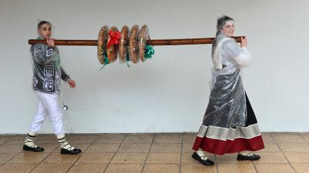 Unai De los Santos Rodríguez y Ane Arregui Larraza portan el palo con las tortas ensartadas.