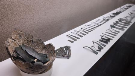 La vitrina con las piezas de bronce halladas en el yacimiento de Tafalla. A la izquierda, la vasija donde estaban guardadas, con los lingotes agrupados de diez en diez.