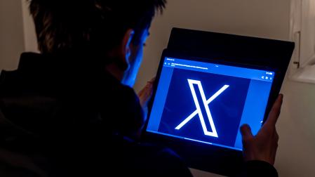 Un joven usa una tablet en la que se ve el logo de la red social X, antes Twitter