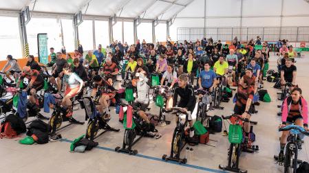 Los participantes en el maratón solidario de spinning pedalean en el patinódromo municipal
