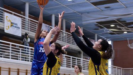 Aixa Wone, que anotó seis puntos, lanza a canasta ante dos jugadoras del Melilla La Salle